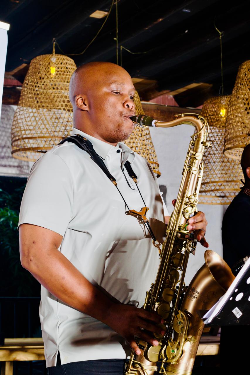 Saxophonist performing with a gold saxophone at a warmly lit venue